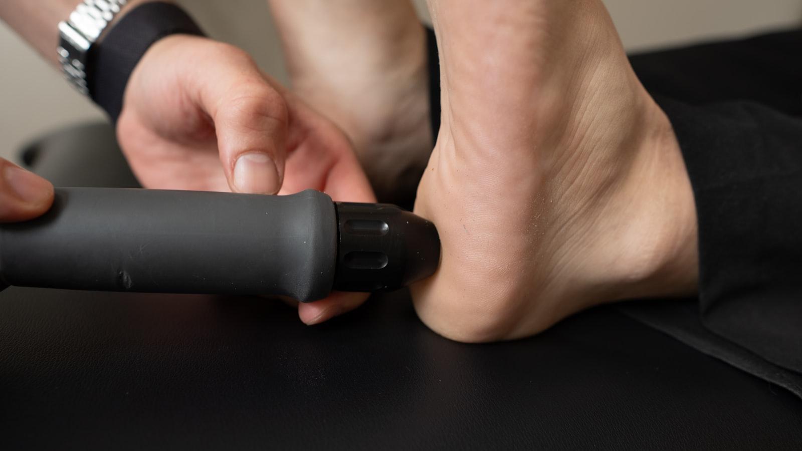 A therapist treating a patient's heel with a handheld therapy device